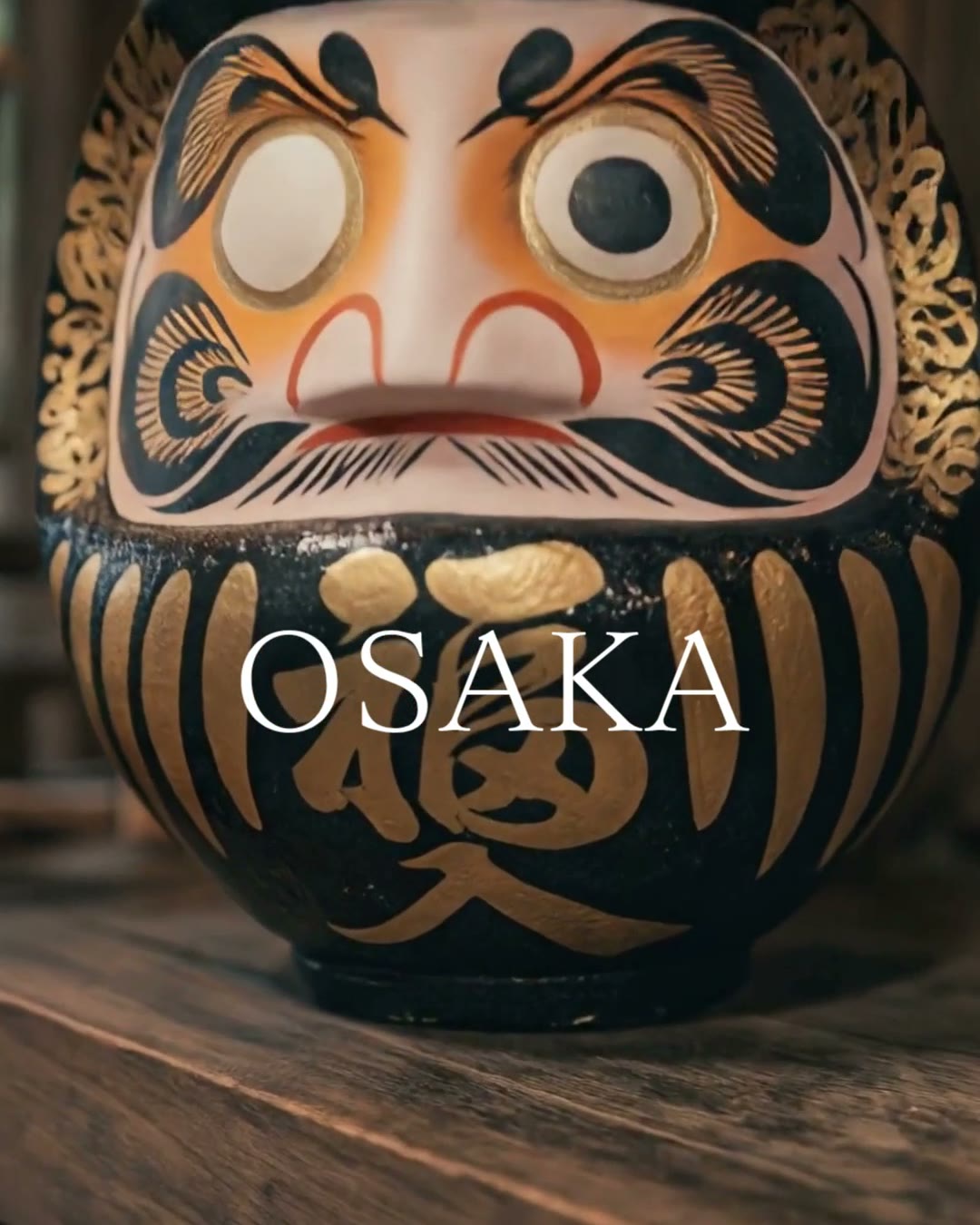 A gold and black Daruma doll on an artisan's shelf